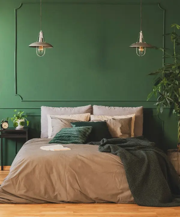 A cozy bedroom featuring green walls and a neatly made bed.
