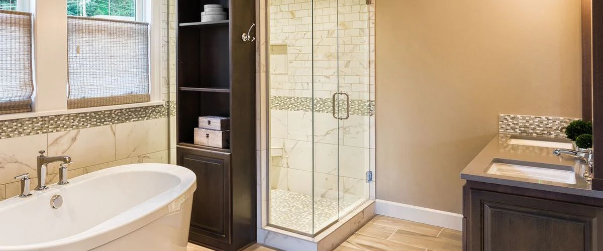 A modern master bathroom featuring a white freestanding soaking tub, a dark wood built-in shelving unit, and a glass-enclosed walk-in shower with marble subway tile.