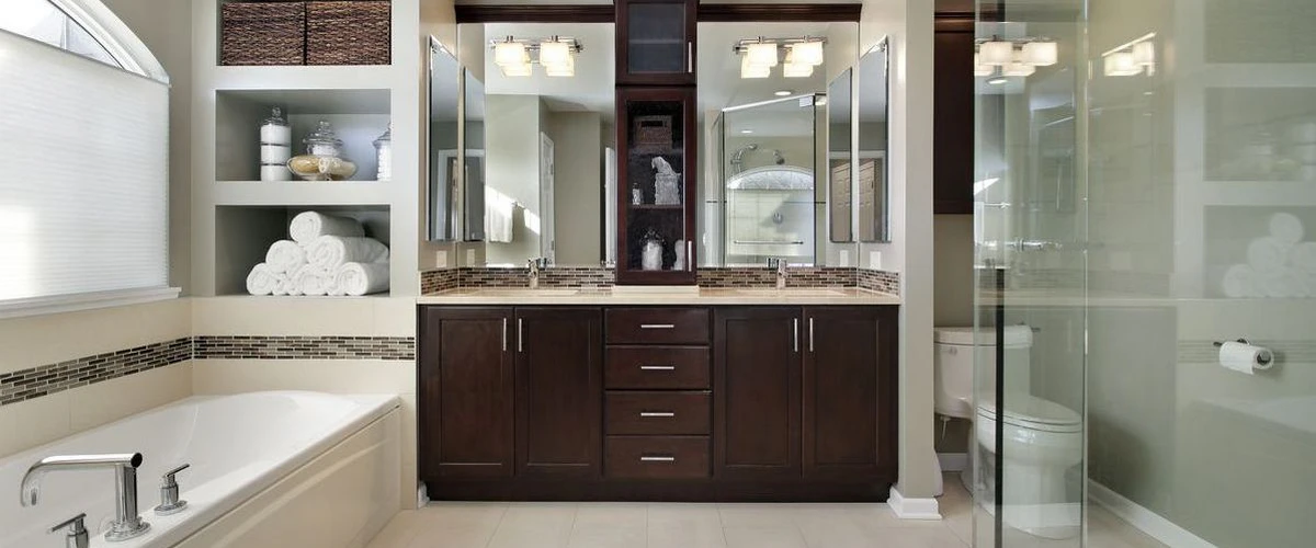 A spacious modern bathroom featuring a dark wood double vanity with marble countertops, a large white soaking tub, built-in shelving with rolled white towels, and a glass-enclosed walk-in shower.