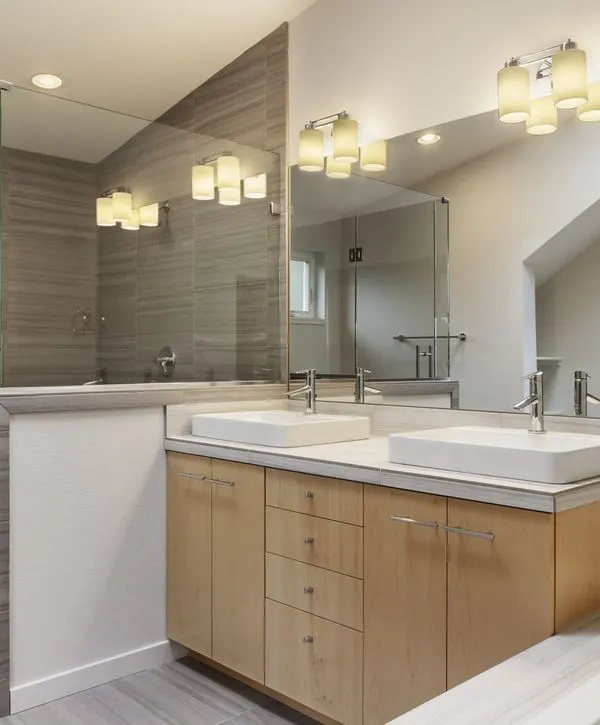 A modern bathroom featuring a light wood double vanity with white vessel sinks and large mirrors, reflecting a professional bathroom remodeling in Bellevue, NE.