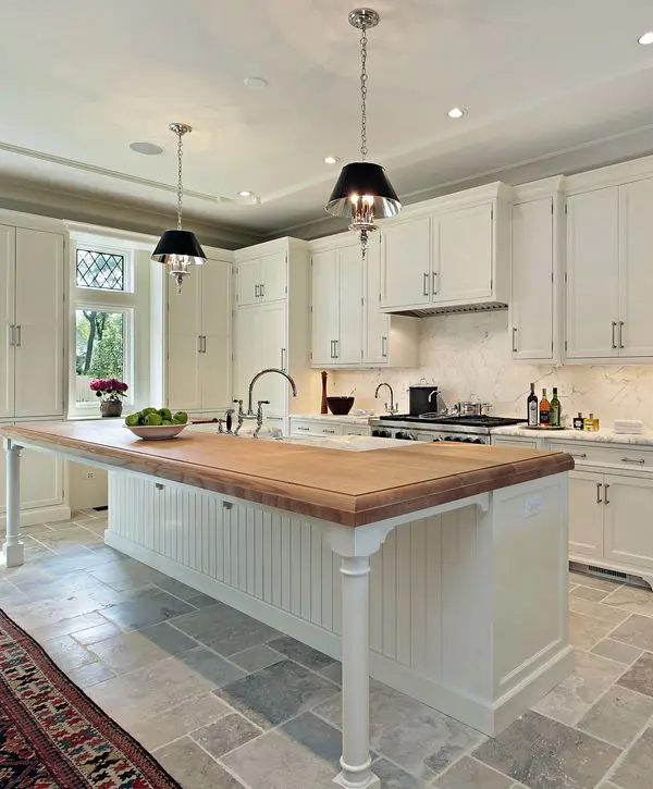 Spacious white kitchen featuring a large wood-top island, marble backsplash, and elegant black pendant lighting for a kitchen remodeling project in La Vista, NE.