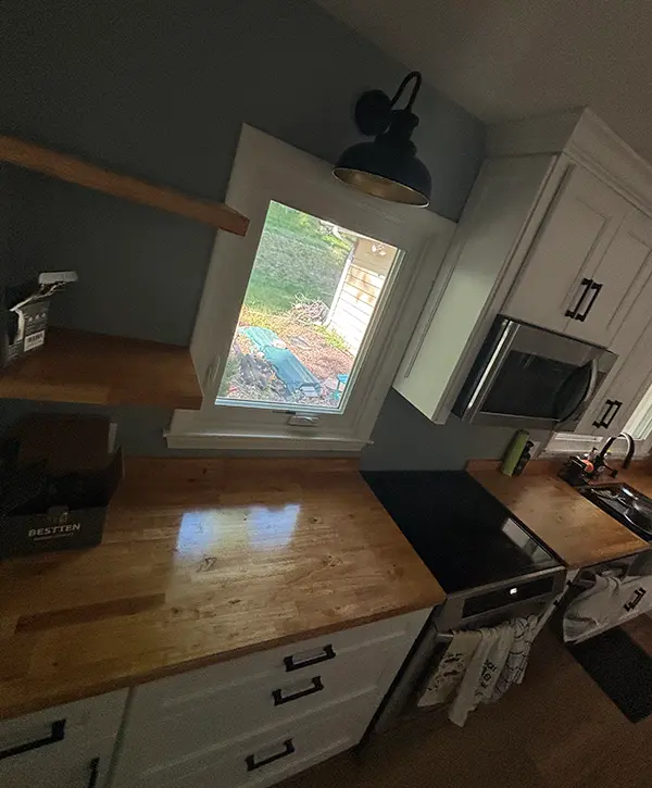 Farmhouse kitchen remodel with butcher block counters, open shelves, and modern black fixtures