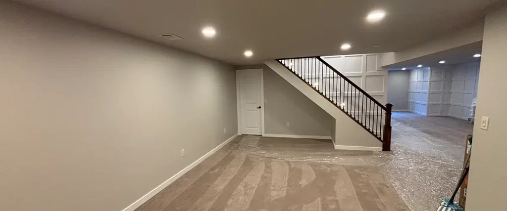 Finished basement living space with carpet flooring, staircase, and recessed lighting