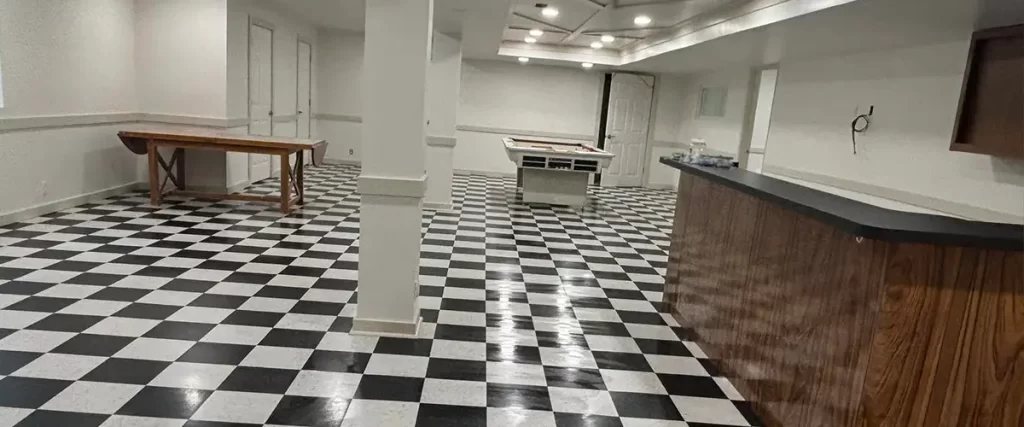 Finished basement with checkerboard flooring, recessed lighting, and custom entertainment bar