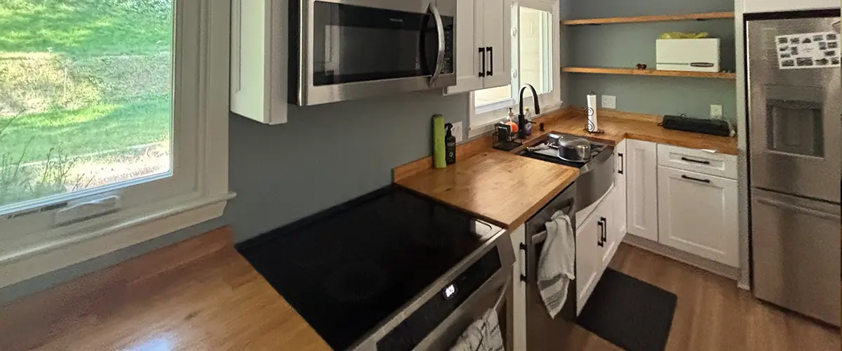 Modern galley kitchen remodel with white shaker cabinets, butcher block counters, and stainless appliances