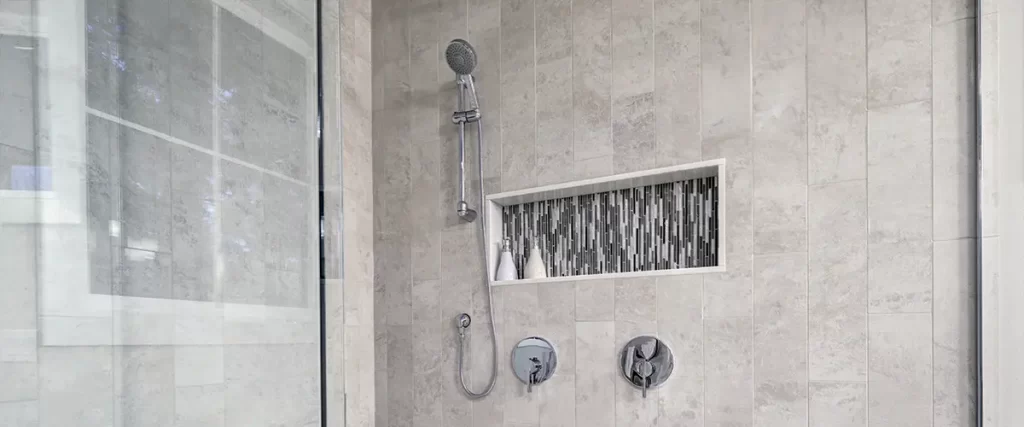 Modern walk-in shower remodel with tile walls, glass enclosure, and recessed storage niche