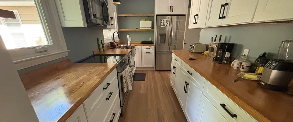 Modern galley kitchen remodel with white shaker cabinets, butcher block counters, and stainless appliances